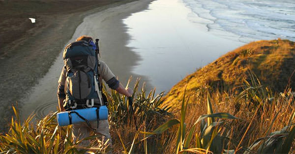 person with backpack hiking to a beach