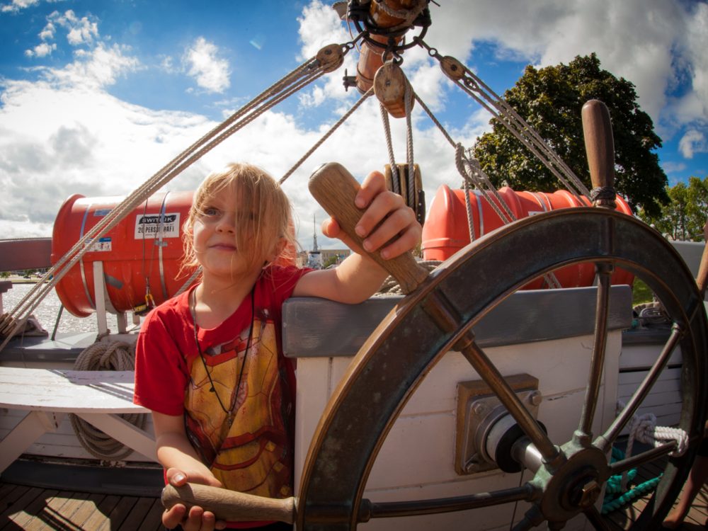A young girl holds a ship’s wheel. Credit: Matt McIntosh/ NOAA