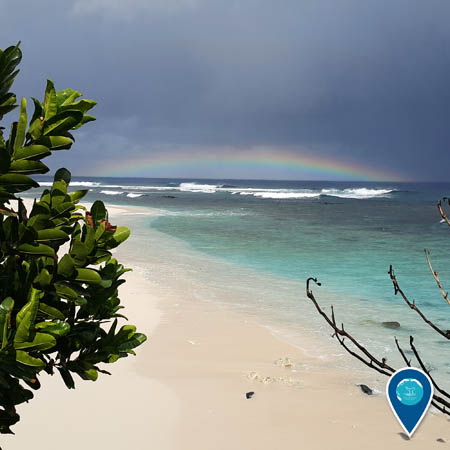 shoreline of american samoa, a rainbow can be seen in the background