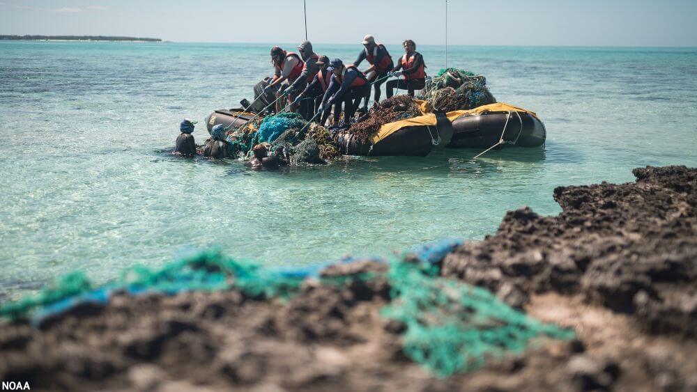 A crew removes debris from the water at Midway Atoll (Kuaihelani, Pihemanu) during a 2018 marine debris removal mission.