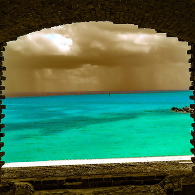 the ocean through an opening in a brick wall