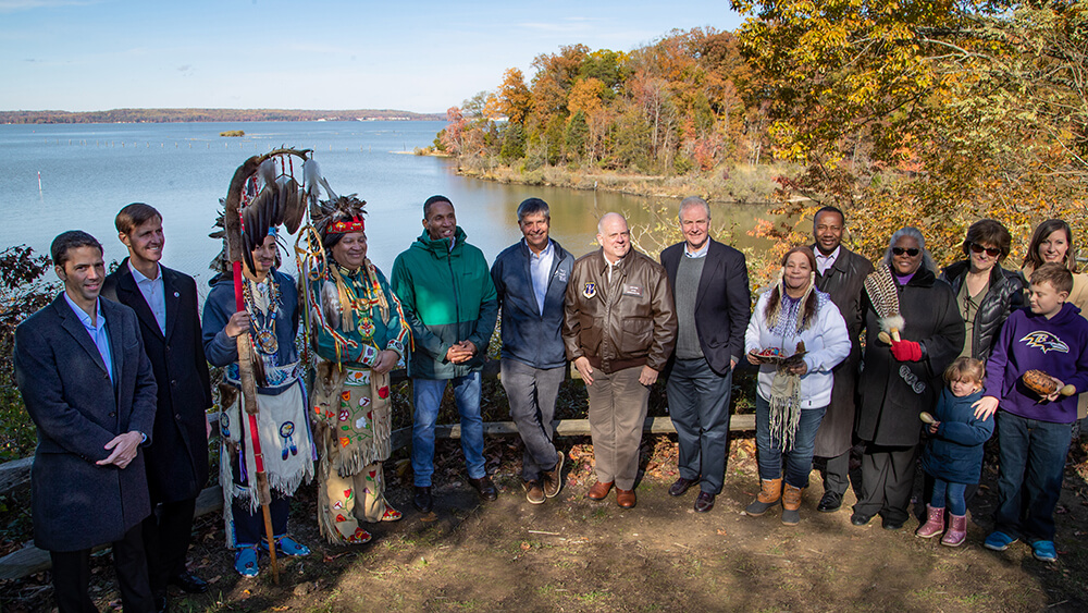 A group of people pose for a photo in front of Mallows Bay-Potomac River National Marine Sanctuary