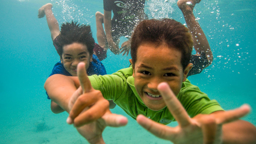 two kids smiling under the water towards the camera