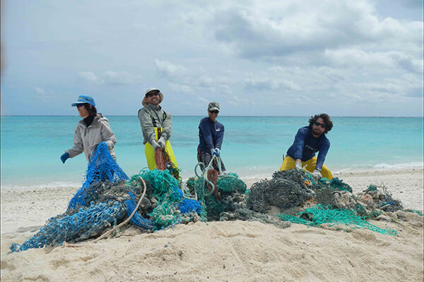 Four people removing fishing nets from the beach
