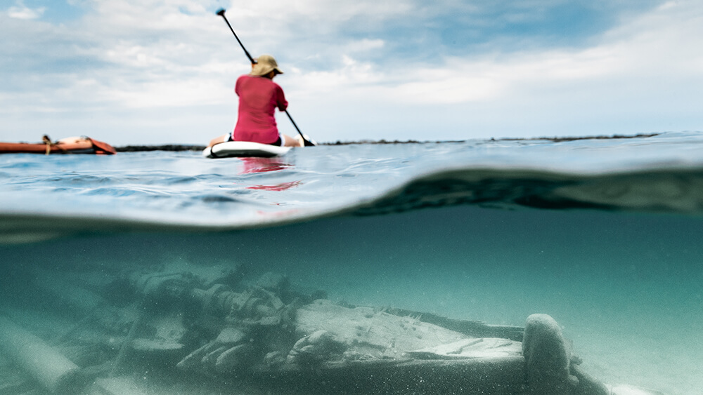 a person kayaking over a submerged shipwreck