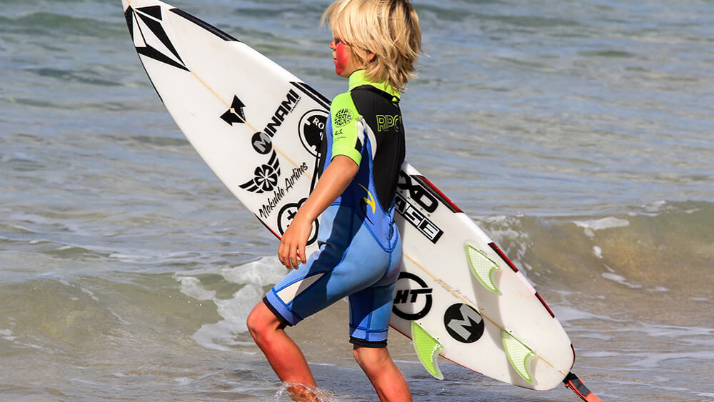 Child runs into the water to surf